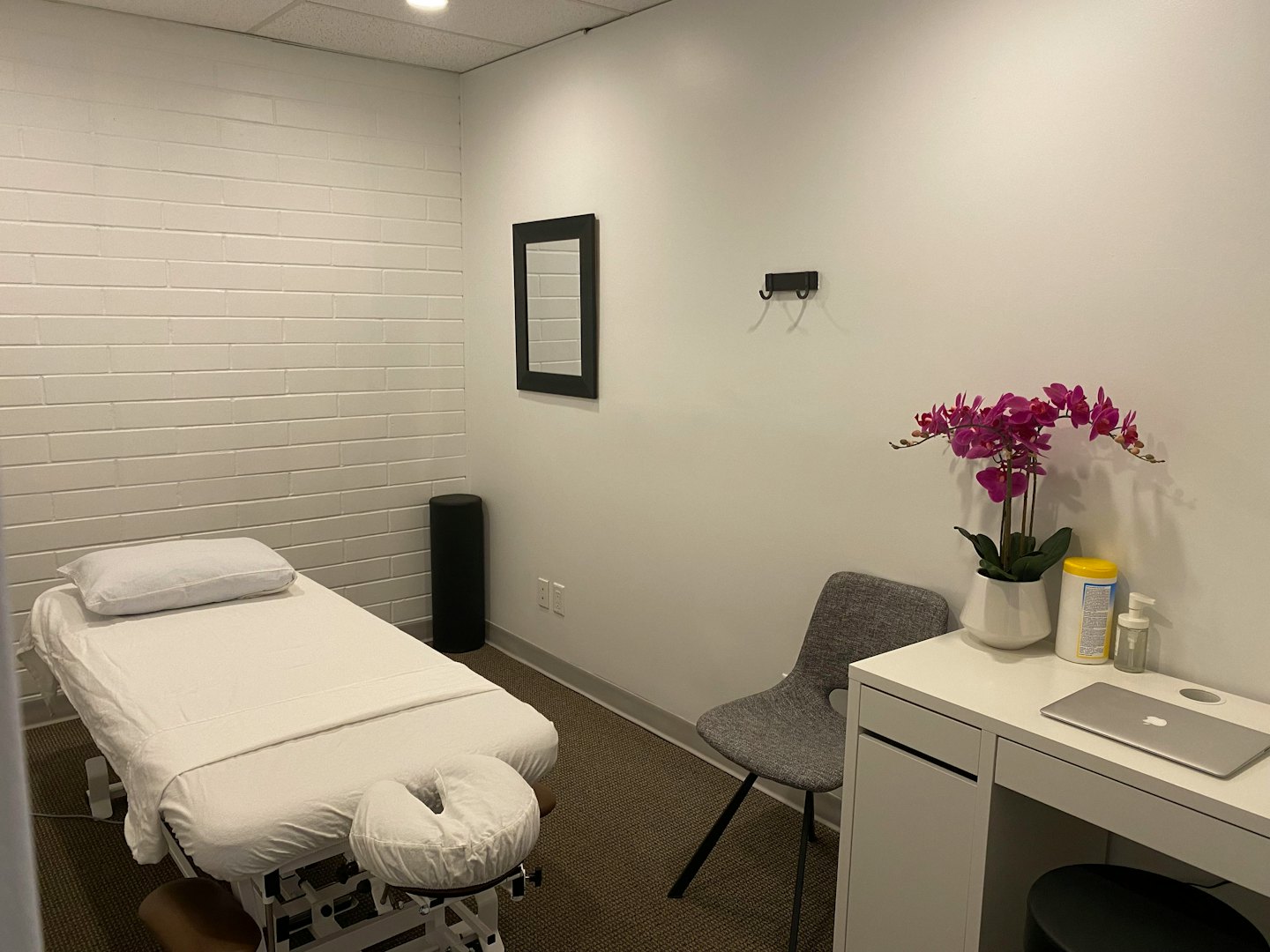 Therapieraum mit Behandlungsliege, Stuhl und Schreibtisch.
