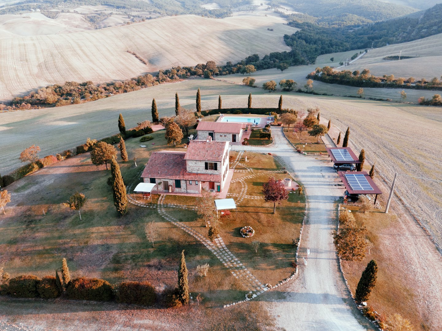 Luftaufnahme eines ländlichen Anwesens mit Steingebäuden und Solarparkplätzen.