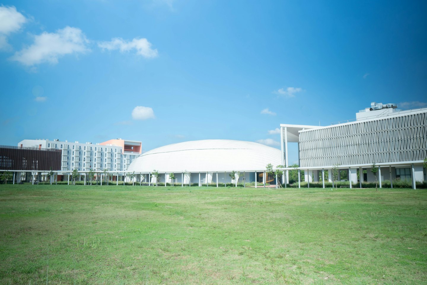 Moderne Campusgebäude umgeben eine große grüne Rasenfläche.
